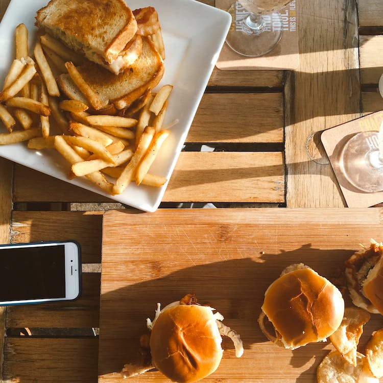 A picture with three sandwiches on a plate with fries. Three burgers lay on the table.